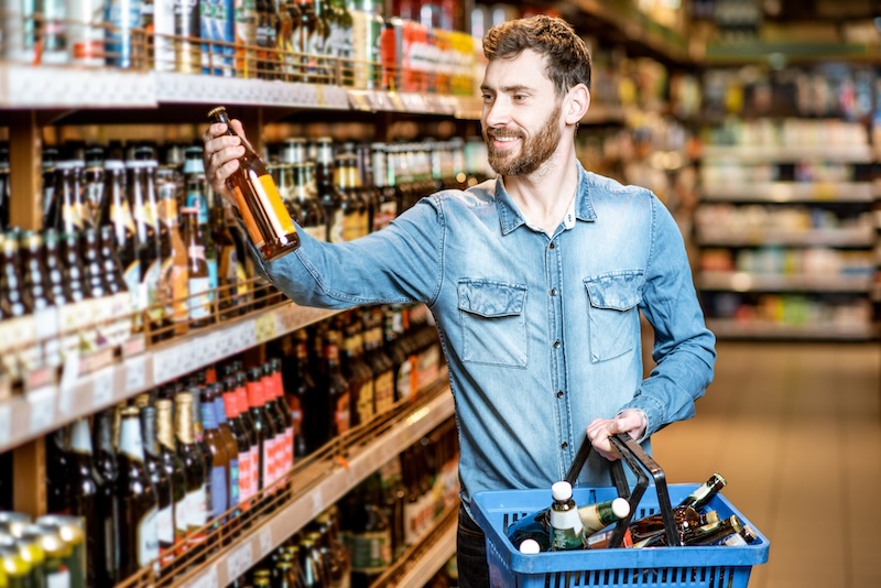 Mann vor Bierregal im Supermarkt