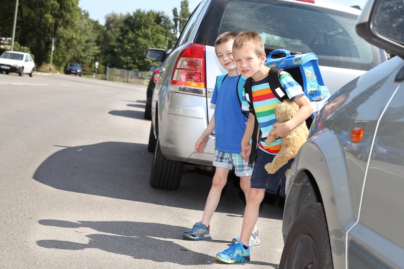 Schulkinder überqueren Straßen zwischen Autos