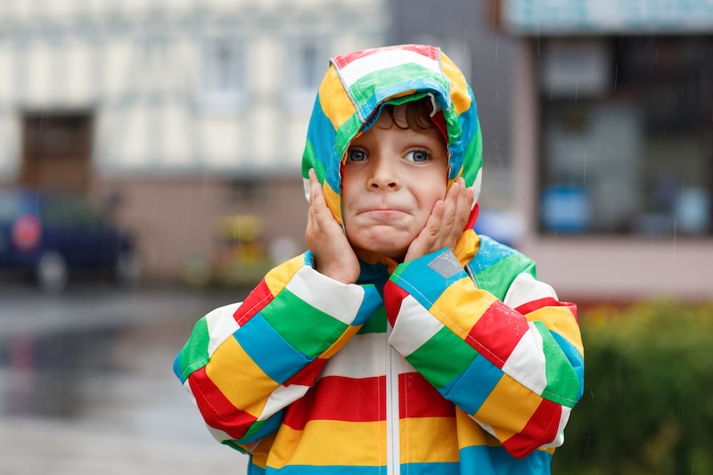 Junge mit bunter Regenjacke im Regen